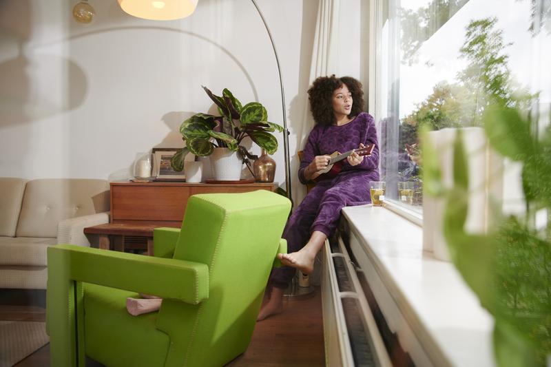 Gasprijs per m3 - mevrouw zit op warme radiator naar buiten te kijken door het raam