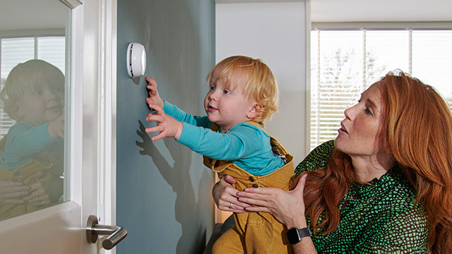 Vast contract tarieven voor mensen die rust willen, zoals een hier een jong gezin waarbij de moeder een baby optilt om aan de thermostaat te draaien