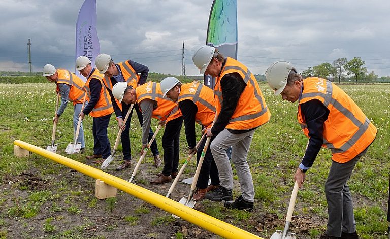 Meerdere mensen die samen een schop in de grond zetten